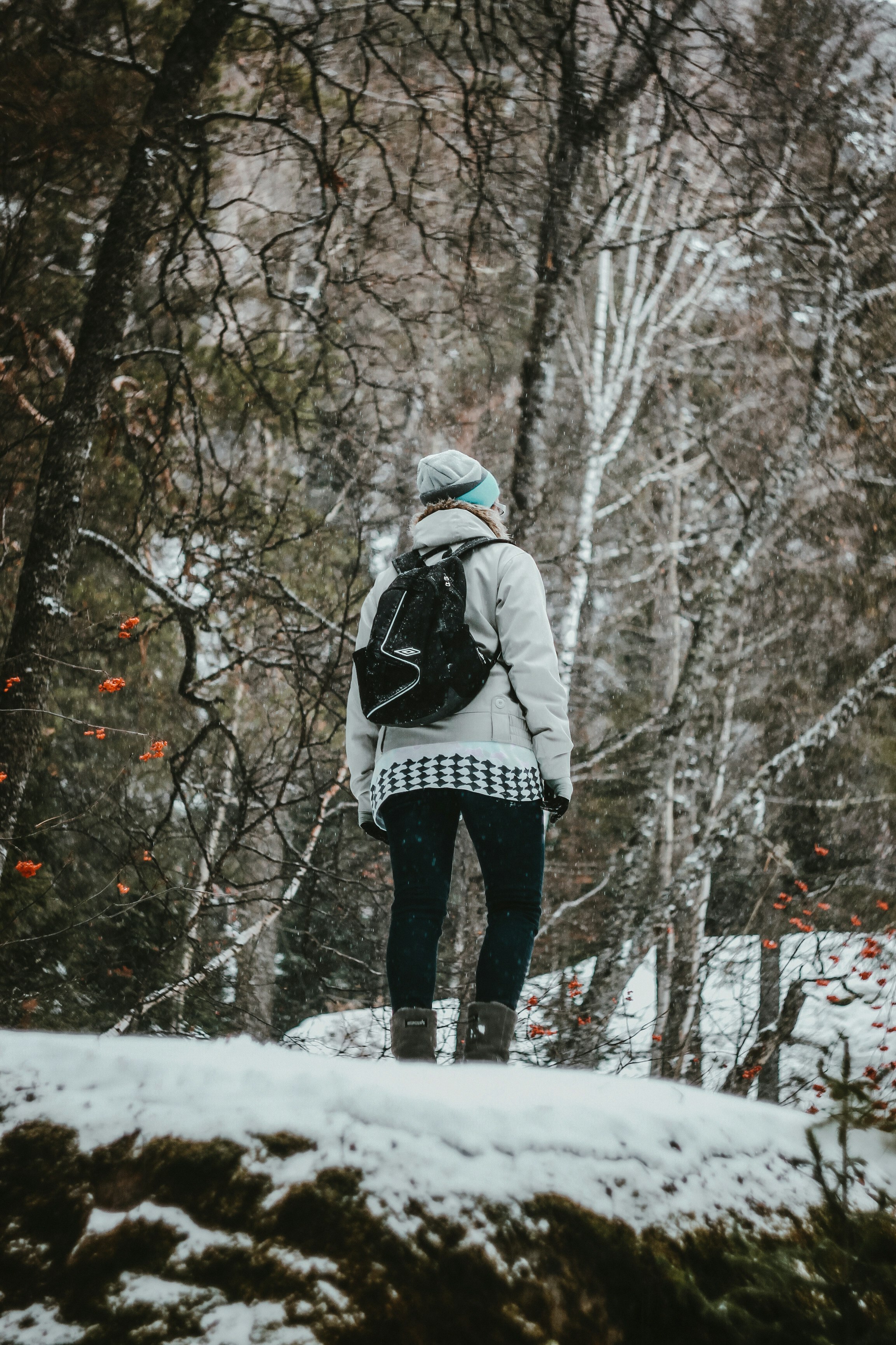 person in white and black jacket and black pants standing on snow covered ground